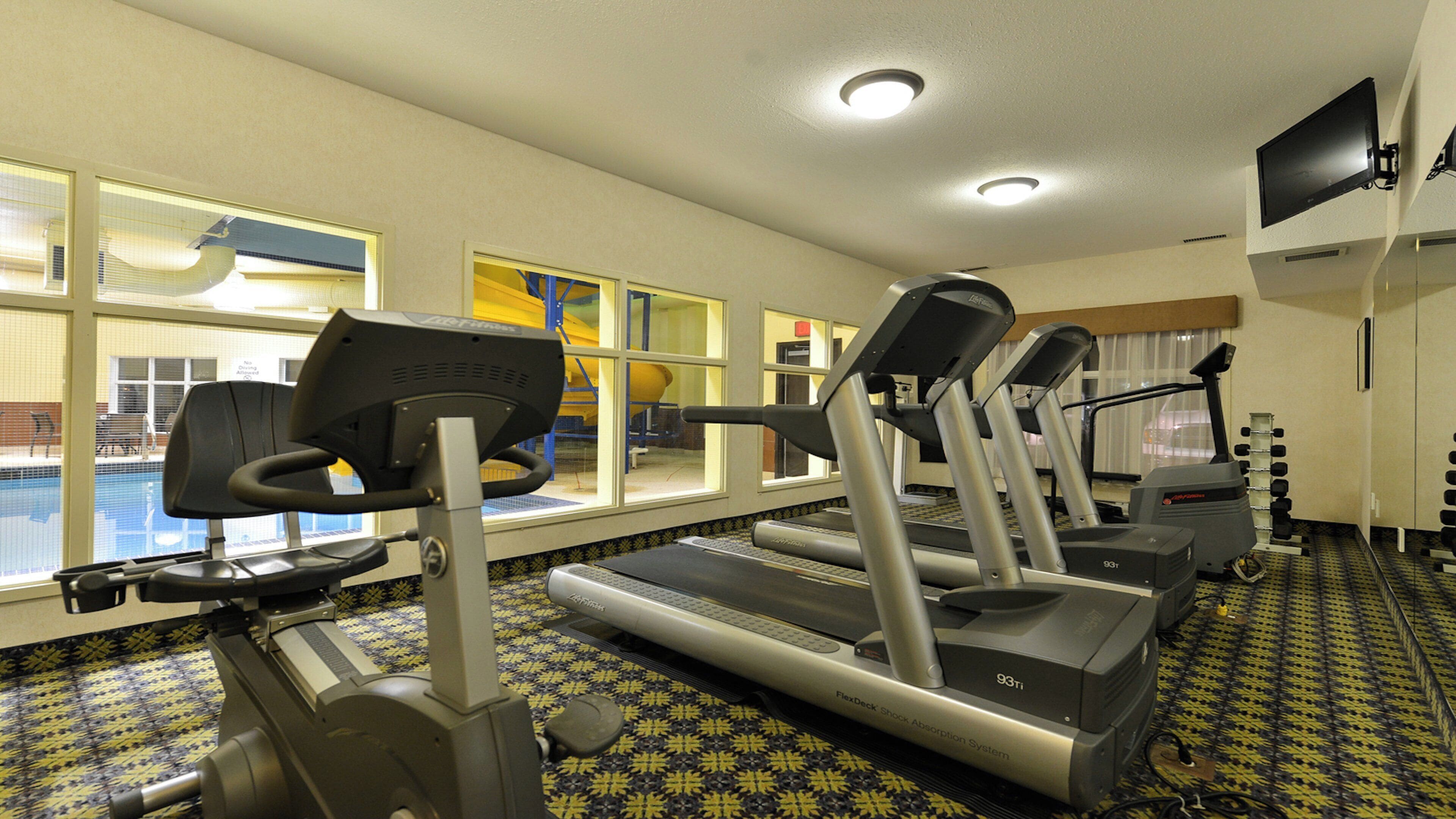 Une salle de sport équipée de tapis de course, d’un vélo d’appartement et d’un support pour haltères.