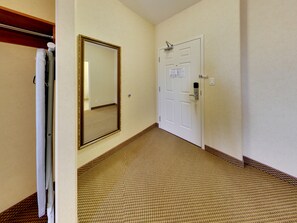 A hallway with a carpeted floor, a white door with a lock, and a large mirror on the wall. - Holiday Inn Express & Suites Edmonton International Airport by IHG (Nisku)