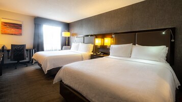 Habitación de hotel con dos camas, un escritorio y una silla.