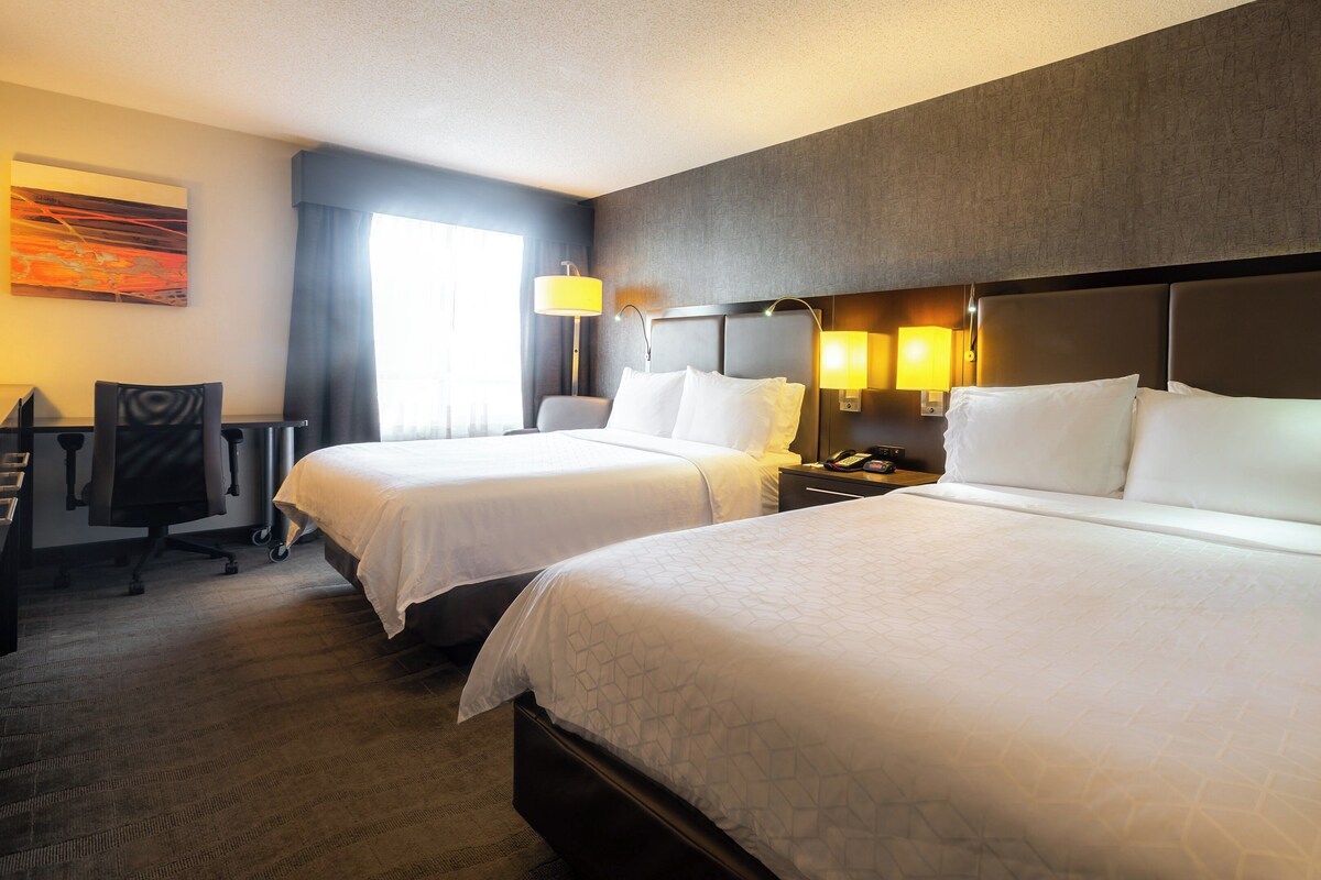 A hotel room with two beds, a desk, and a chair.