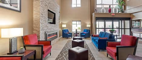A spacious lobby with a stone wall, comfortable seating, a fireplace, and large windows.
