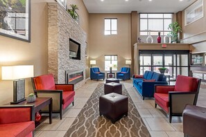 A spacious lobby with a stone wall, comfortable seating, a fireplace, and large windows. - Comfort Inn & Suites Canton Riverstone Area (Canton)
