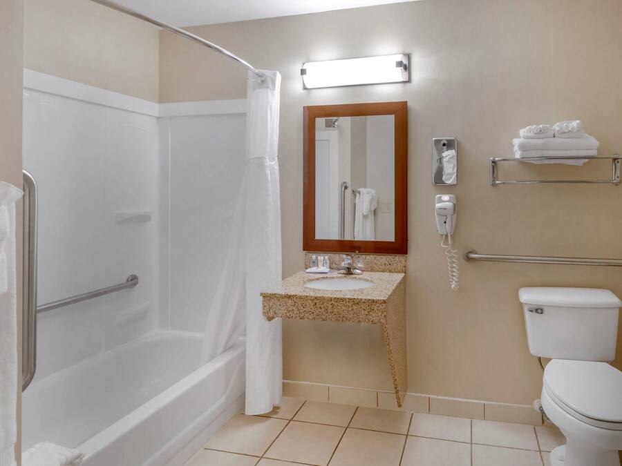 A bathroom with a shower, toilet, sink, and a mirror.