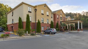 A multi-story hotel with a beige facade, parking lot, and a covered entrance. - Comfort Inn & Suites Canton Riverstone Area (Canton)