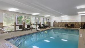 A swimming pool with lounge chairs, a changing room, and large windows with a forest view. - Comfort Inn & Suites Canton Riverstone Area (Canton)
