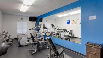 Une salle de sport équipée de matériel d’exercice, dotée d’un grand miroir et d’un mur d’accent bleu.