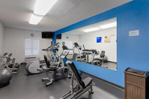 Un gimnasio con equipo de ejercicio, un espejo grande y una pared de acento azul.