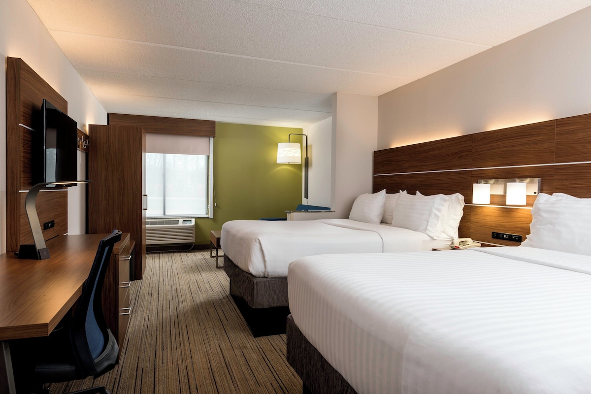 Une chambre d’hôtel avec deux lits, un bureau, une télévision et une fenêtre.