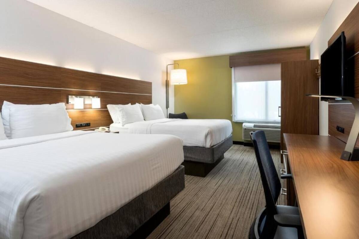 Een hotelkamer met twee bedden, een bureau, een stoel, een televisie en een raam.