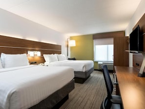 Une chambre d’hôtel avec deux lits, un bureau, une chaise, une télévision et une fenêtre.