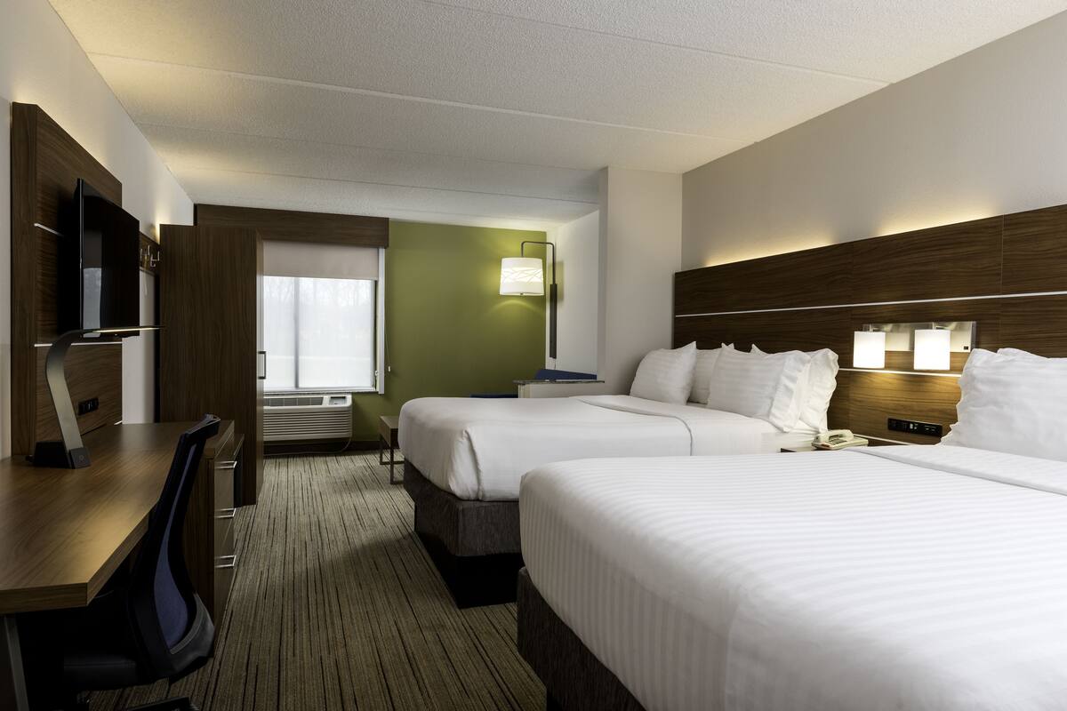 Een hotelkamer met twee bedden, een bureau, een televisie en een raam met uitzicht.
