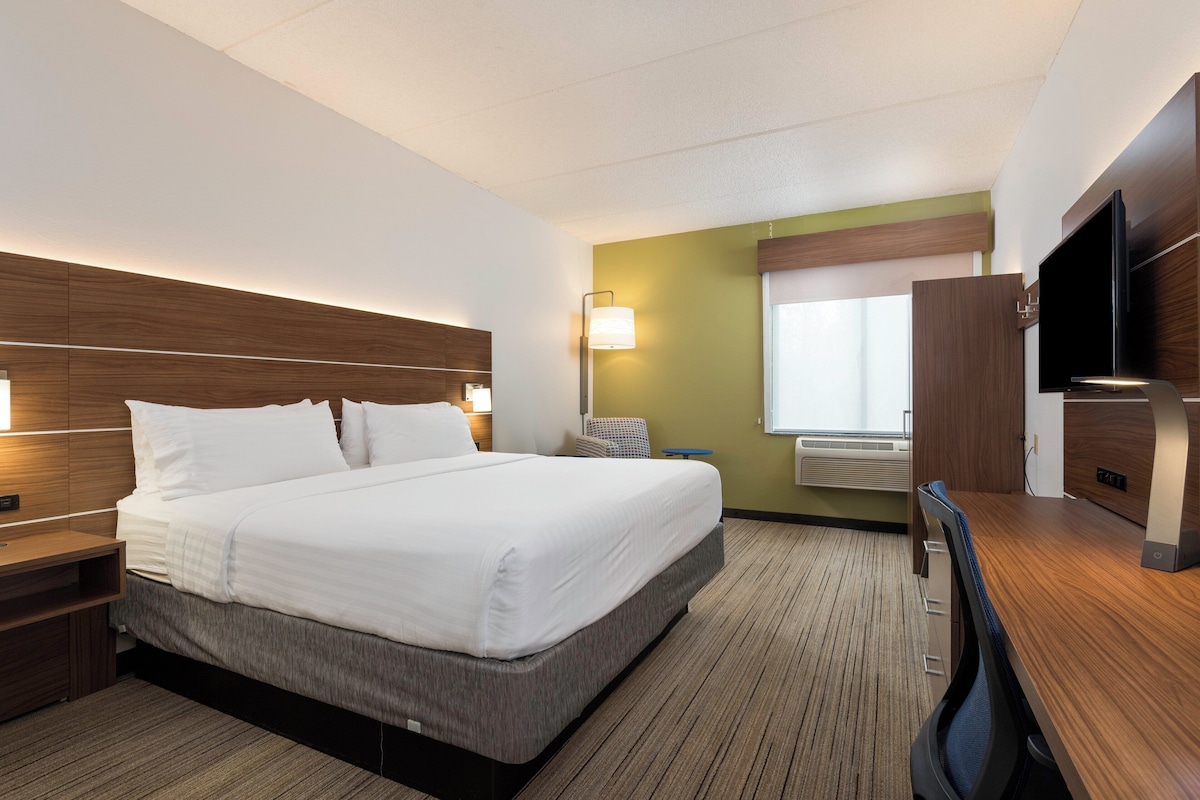 Une chambre d’hôtel avec un lit, des tables de chevet, un bureau, une chaise, une télévision et une fenêtre.
