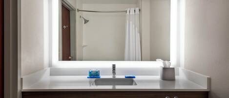 Un baño con lavamanos blanco, espejo y barra para toallas.