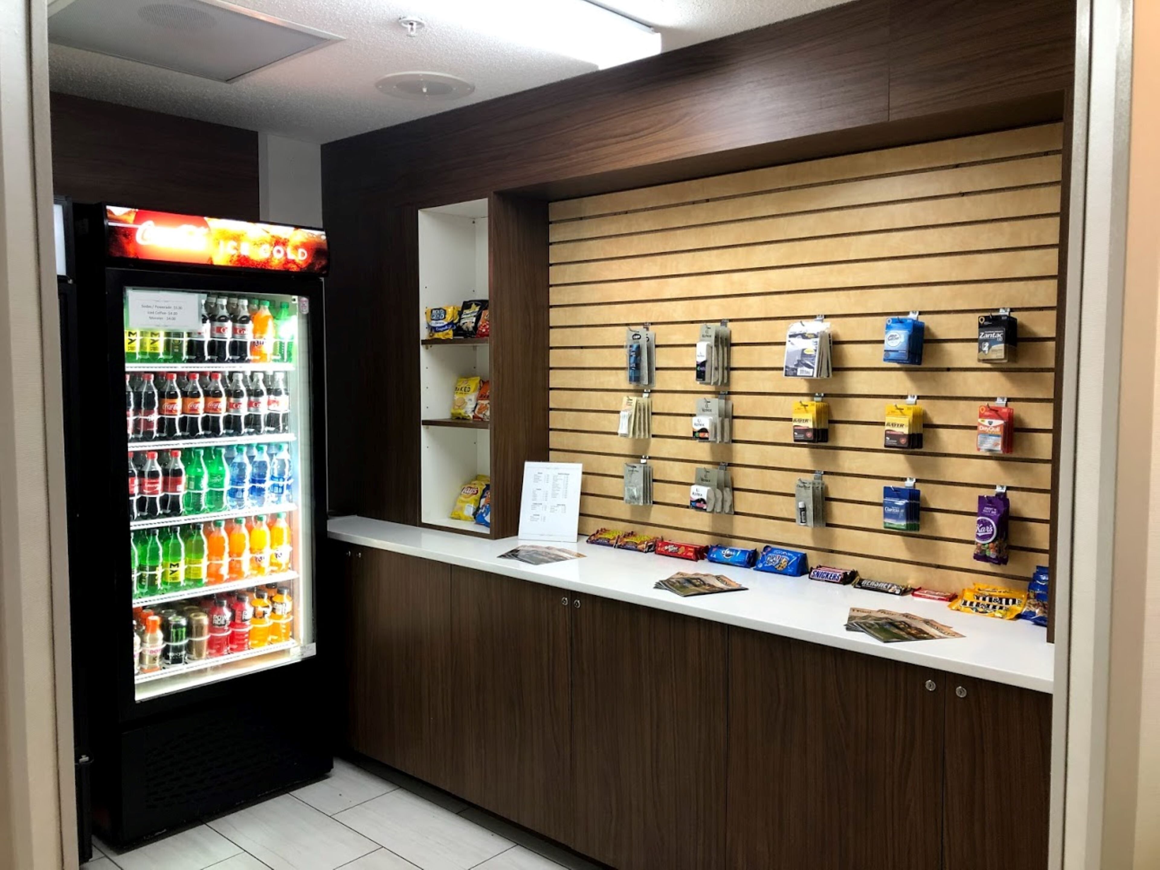 A vending machine with various drinks and snacks, a counter with a display of packaged goods, and a wooden wall with hanging items.