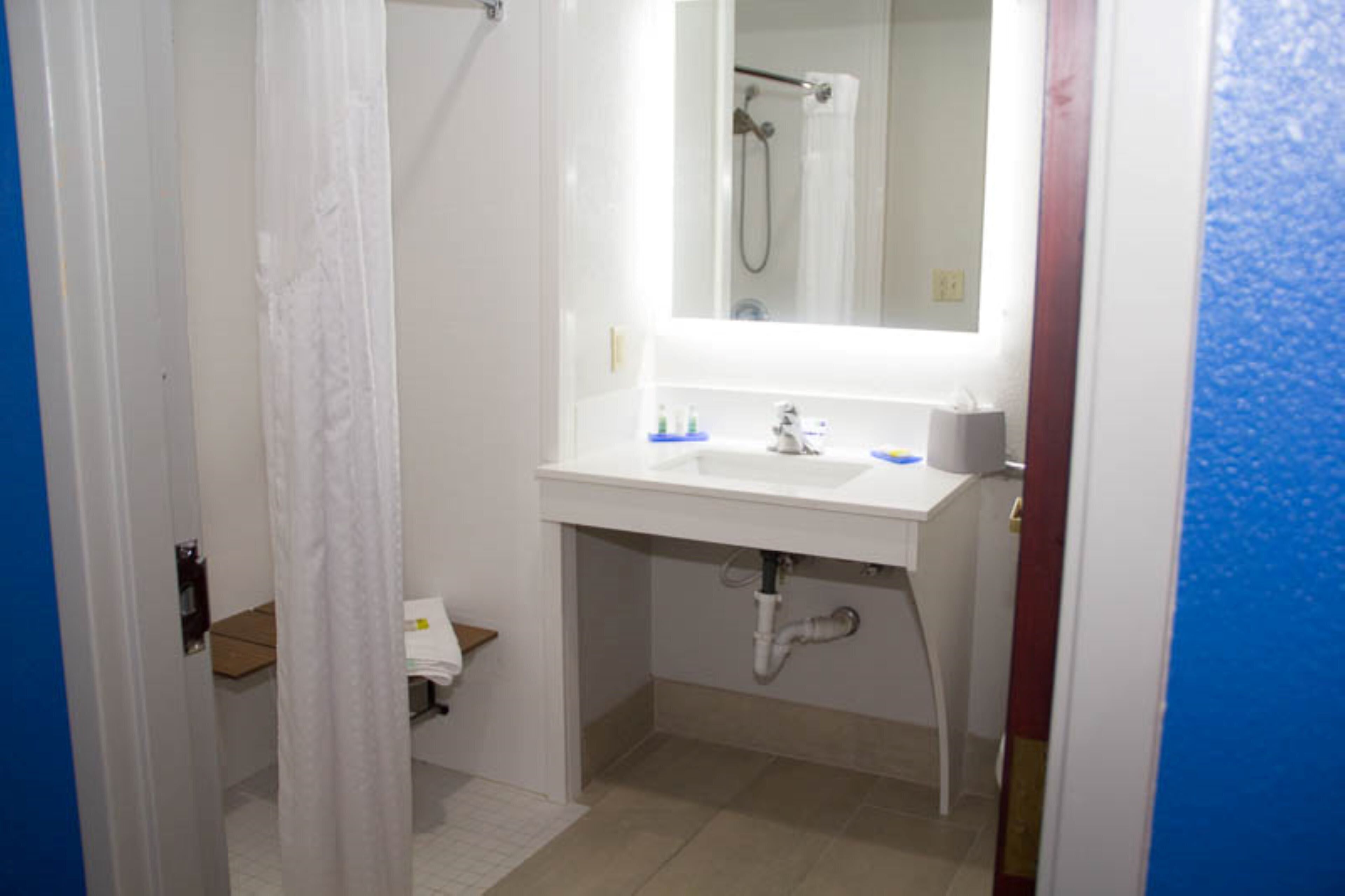 Un baño con lavamanos, espejo y ducha blancos.