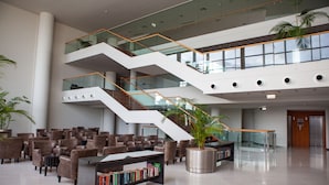 A modern lobby with a central staircase, seating area, and a bookshelf.