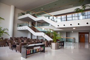 A modern lobby with a central staircase, seating area, and a bookshelf. - Vidamar Resort Madeira (Funchal)