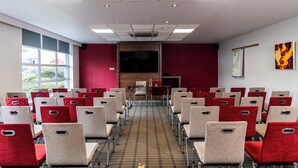 A conference room with rows of chairs, a large screen, and a podium. - Holiday Inn Express Glasgow Airport by IHG (Paisley)