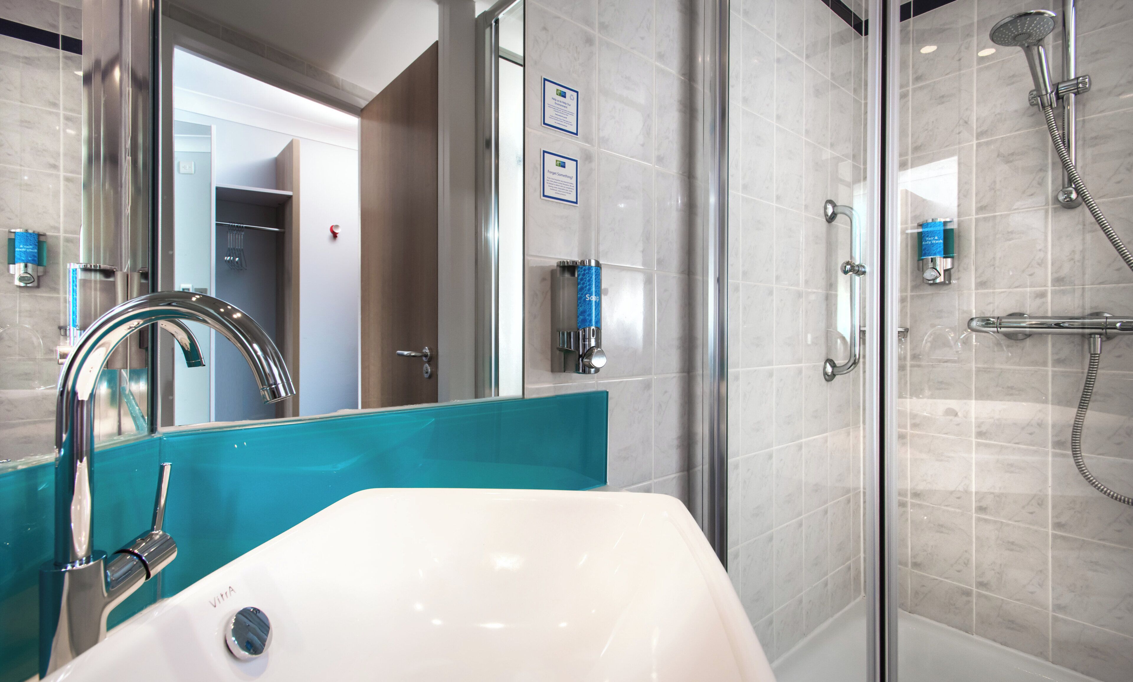 A modern bathroom with a white sink, a glass shower enclosure, and a visible door leading to another room.