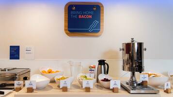 Un bufé de desayuno con diversas opciones de comida y un cartel que indica la disponibilidad de tocino.