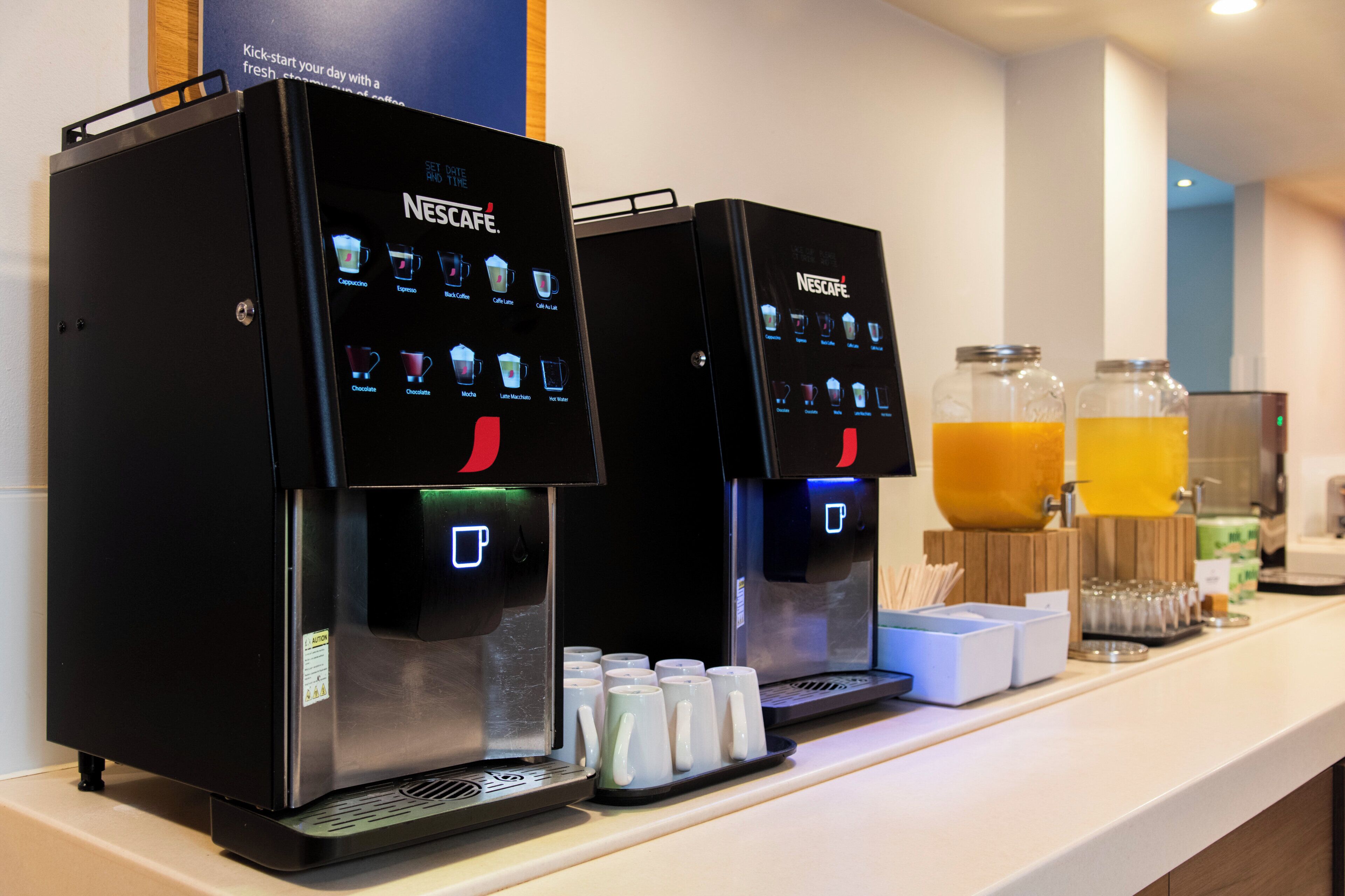 Two Nescafe coffee machines with a selection of coffee options and a water dispenser.