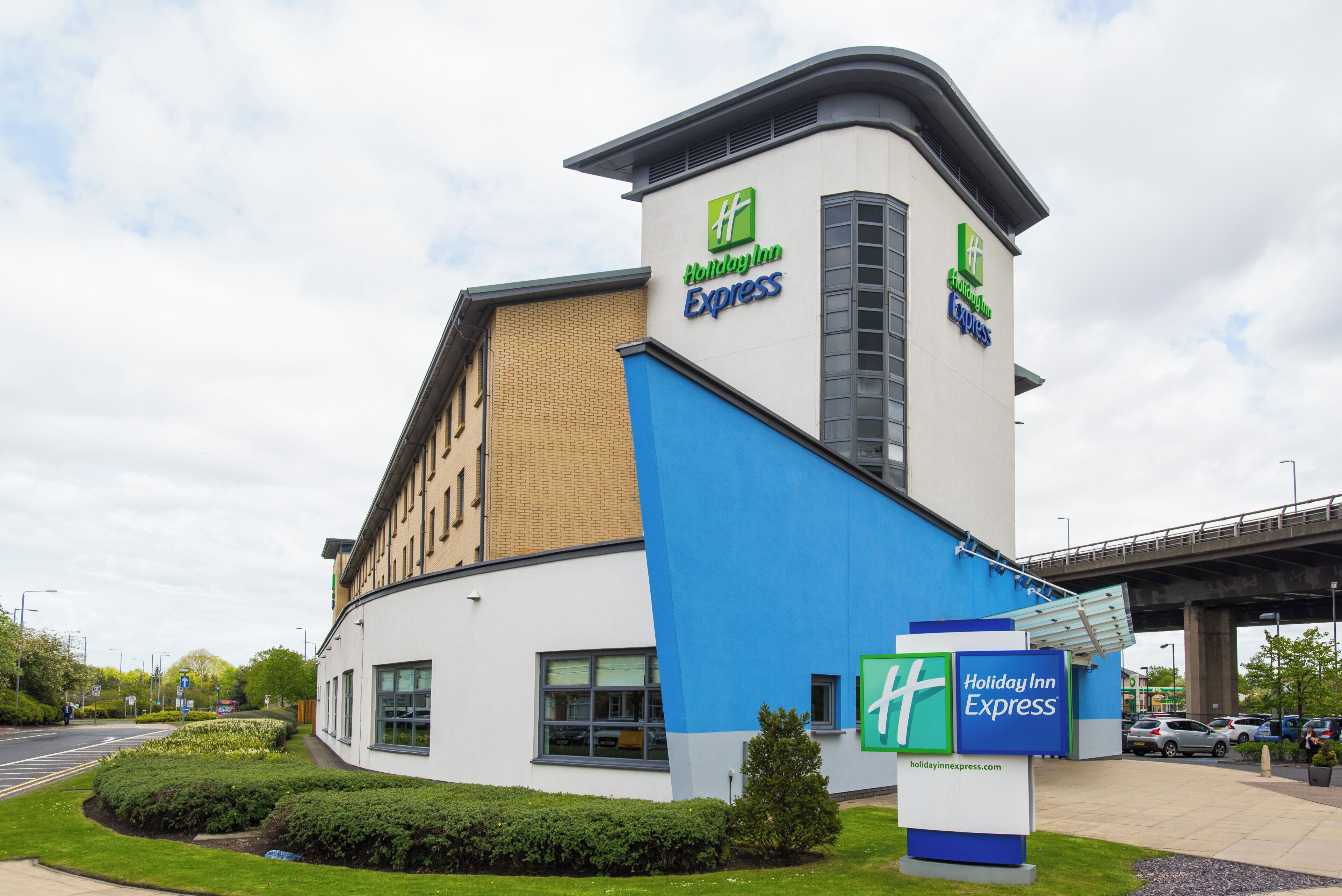 A Holiday Inn Express building with a modern design, featuring a prominent sign and a parking area.