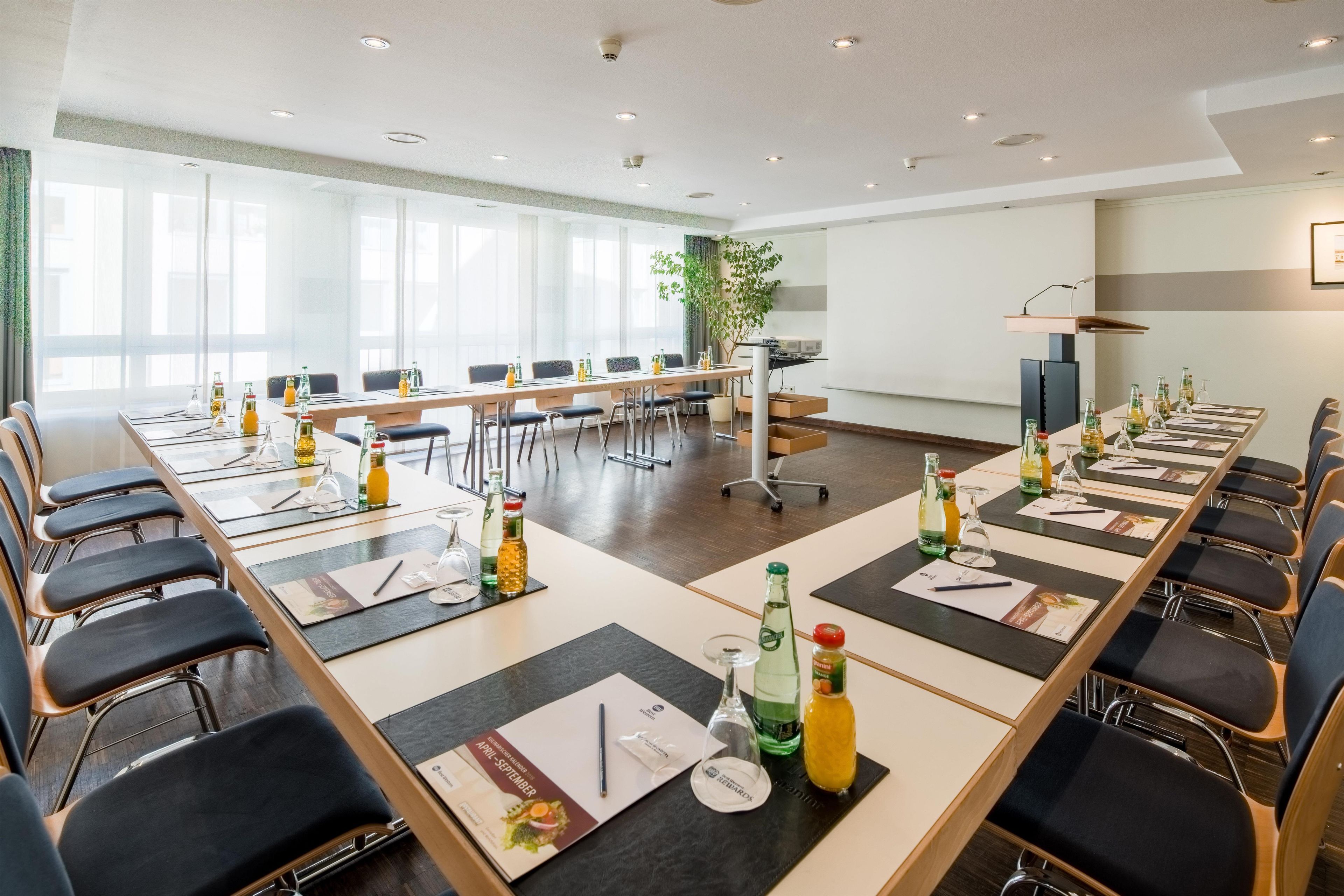 A conference room with long tables, chairs, and various beverages.