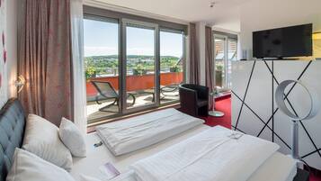 A hotel room with a bed, a TV, a balcony with a view, and a chair.