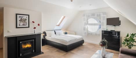 Un dormitorio moderno con chimenea, una cama, un televisor y vistas al cielo.