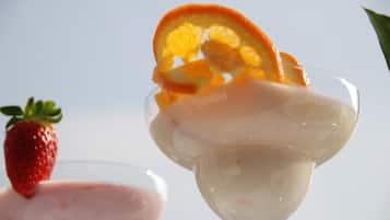 A glass with a creamy dessert topped with a strawberry and orange slice.