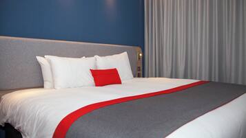 Une chambre d’hôtel avec un grand lit, une tête de lit et un rideau.