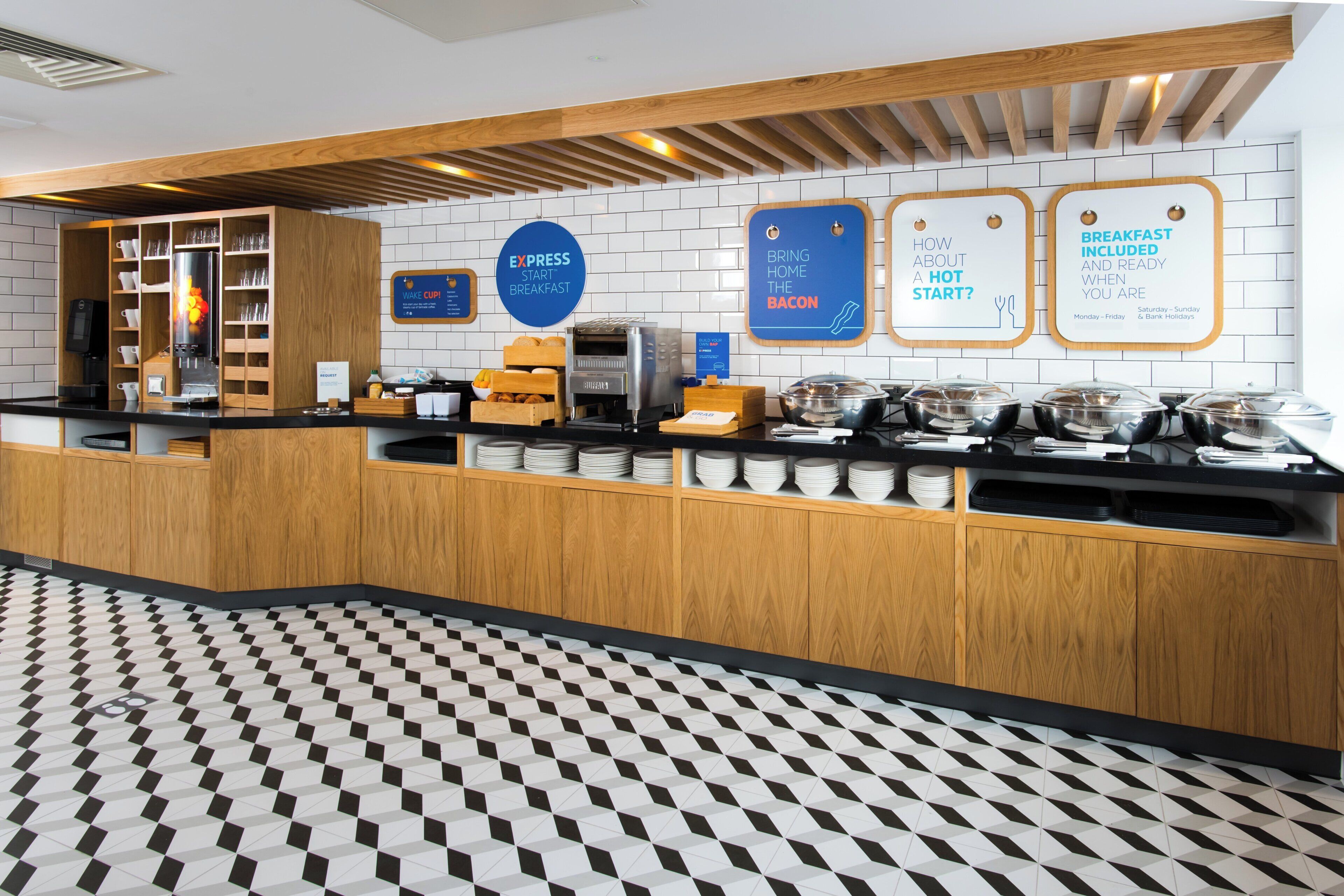 A breakfast bar with a coffee machine, a bread display, and a sign indicating breakfast is included.