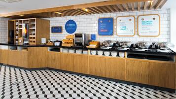 A breakfast bar with a coffee machine, a bread display, and a sign indicating breakfast is included.