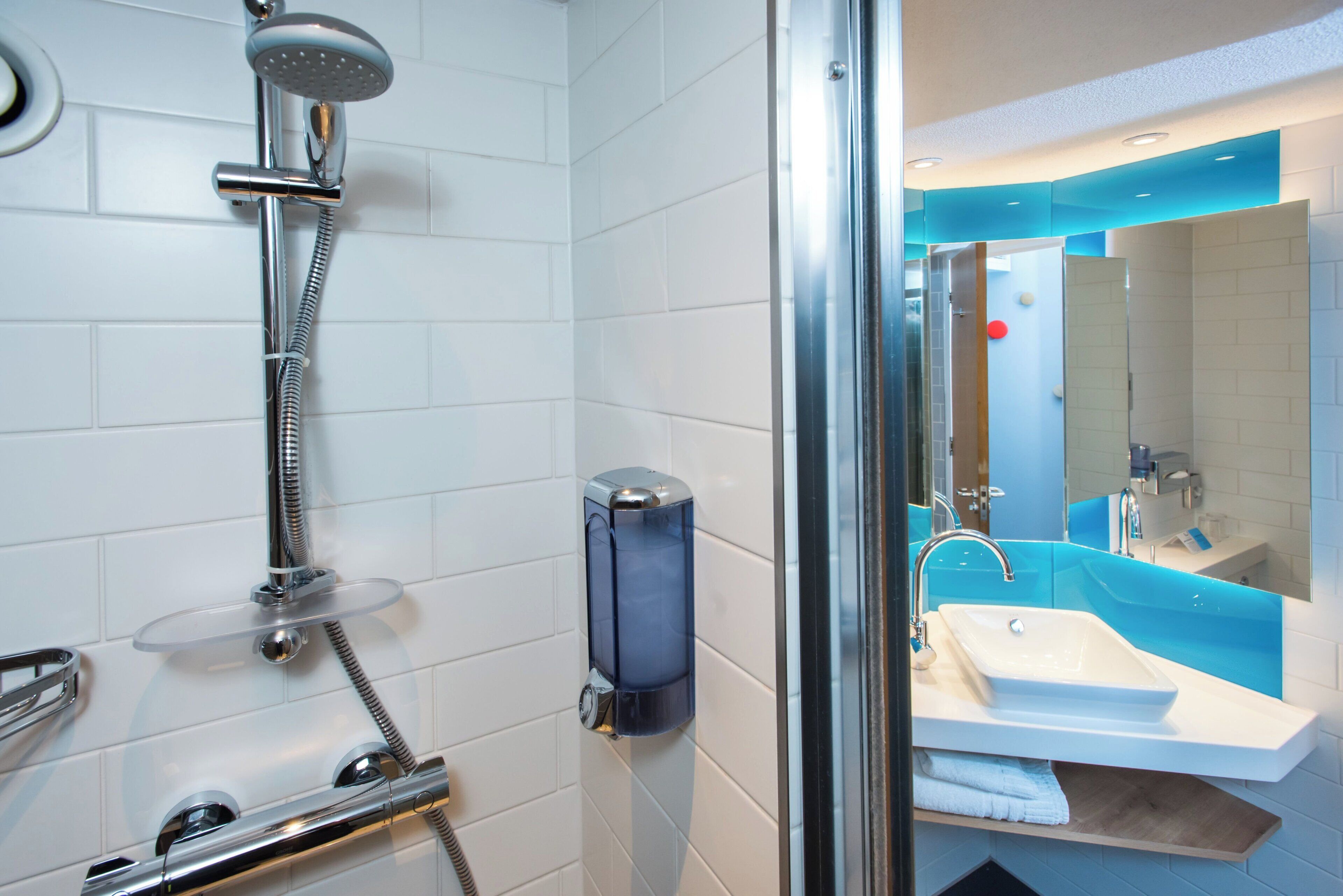 A modern bathroom with a glass-enclosed shower, a white sink, and a blue accent wall.