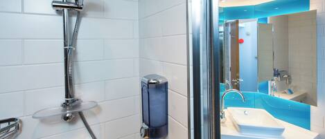 Un baño moderno con ducha de vidrio, lavamanos blanco y pared de acento azul.
