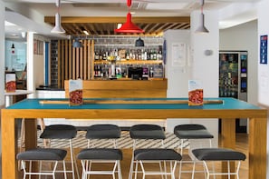 A bar area with a long counter, multiple stools, and a variety of bottles and glasses.