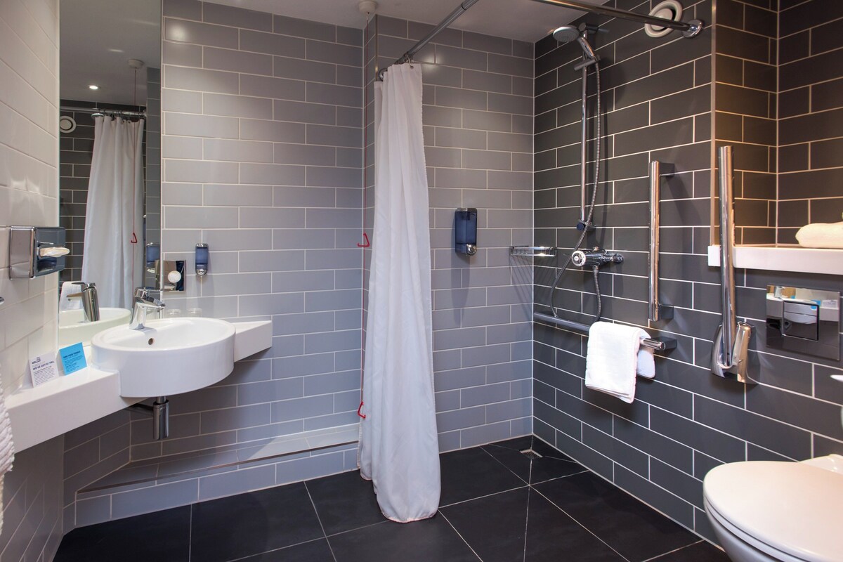 Une salle de bain moderne avec un lavabo blanc, une douche et des toilettes.