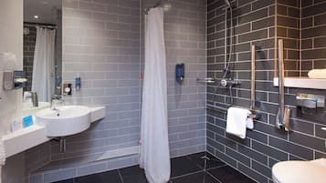 A modern bathroom with a white sink, a shower, and a toilet.