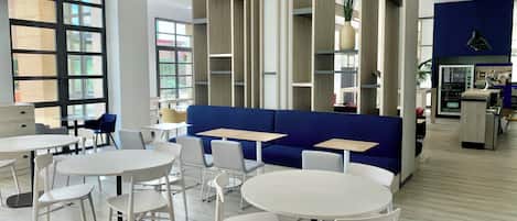 A modern interior with seating arrangements, tables, and a vending machine.
