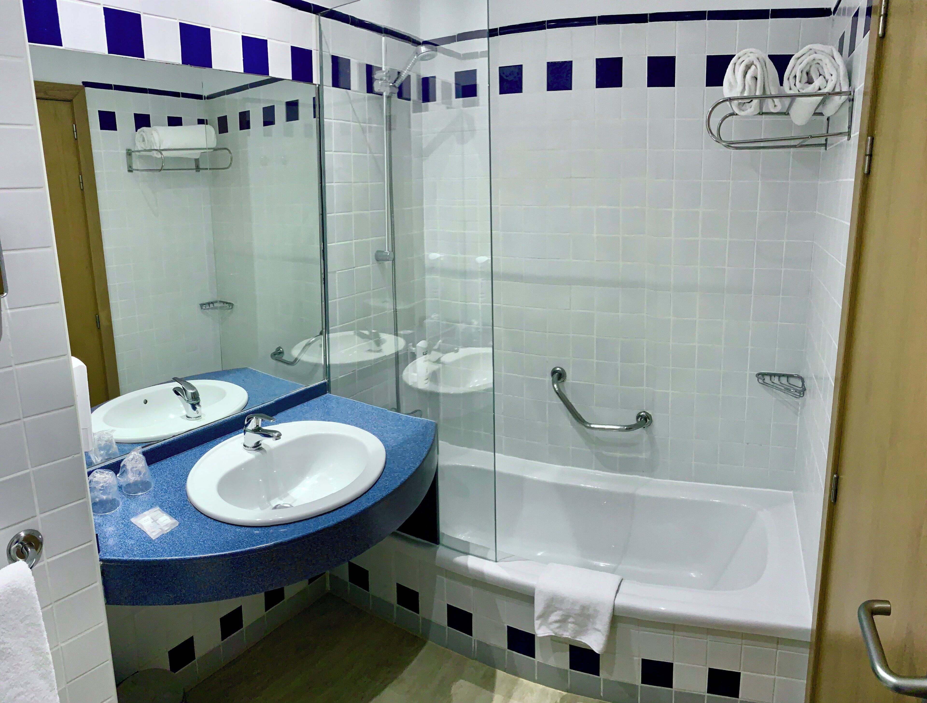 A bathroom with two sinks, a glass-enclosed shower, and a bathtub.
