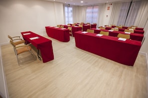 Sala de conferências com várias mesas e cadeiras dispostas em fileiras.