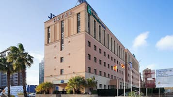 Un hotel de varios pisos con un llamativo letrero que dice 'HOTEL', el logotipo de 'Holiday Inn Express' y varias banderas.