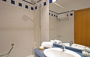 Une salle de bain équipée d’une douche, d’un lavabo, d’un miroir et d’un porte-serviettes.