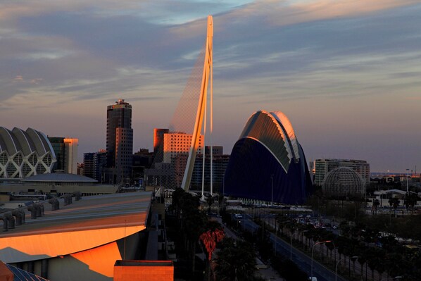 Un paisaje urbano con arquitectura moderna, que incluye un puente destacado y un edificio único con techo curvo.