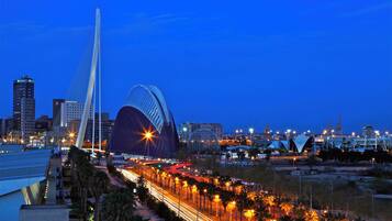 A cityscape at dusk with a prominent bridge and a distinctive building with a curved roof.