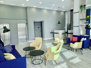 Een modern interieur met een blauwe bank, gele stoelen en een blauwe zithoek.