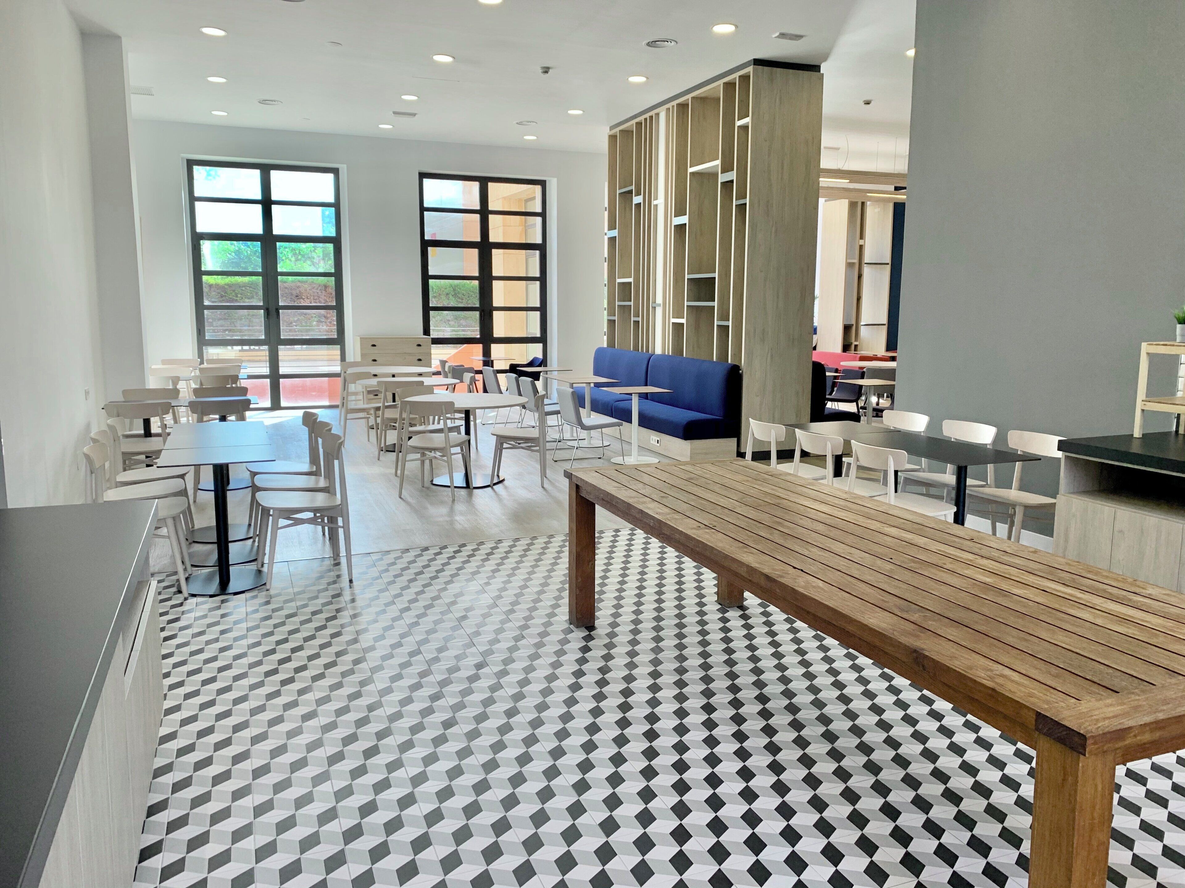 A modern indoor space with multiple seating areas, including tables and chairs, and a large bench.