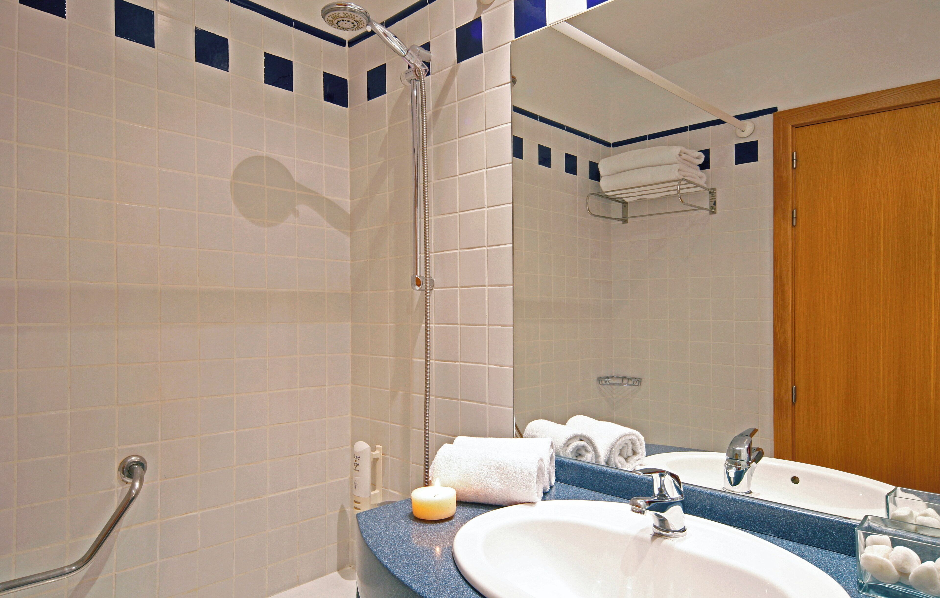 A bathroom with a shower, a sink, and a mirror.