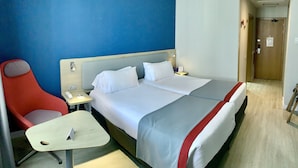 Een hotelkamer met een bed, een bureau, een stoel en een nachtkastje.