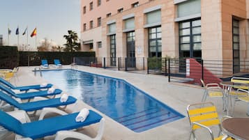 A swimming pool with lounge chairs and a building in the background.